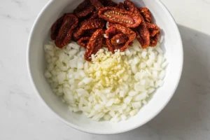 Gewürfelte Zwiebel und Knoblauch sowie geschnittene getrocknete Tomaten in Schale