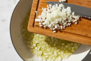 Zwiebel- und Knoblauchwürfel werden in Olivenöl im Topf angedünstet